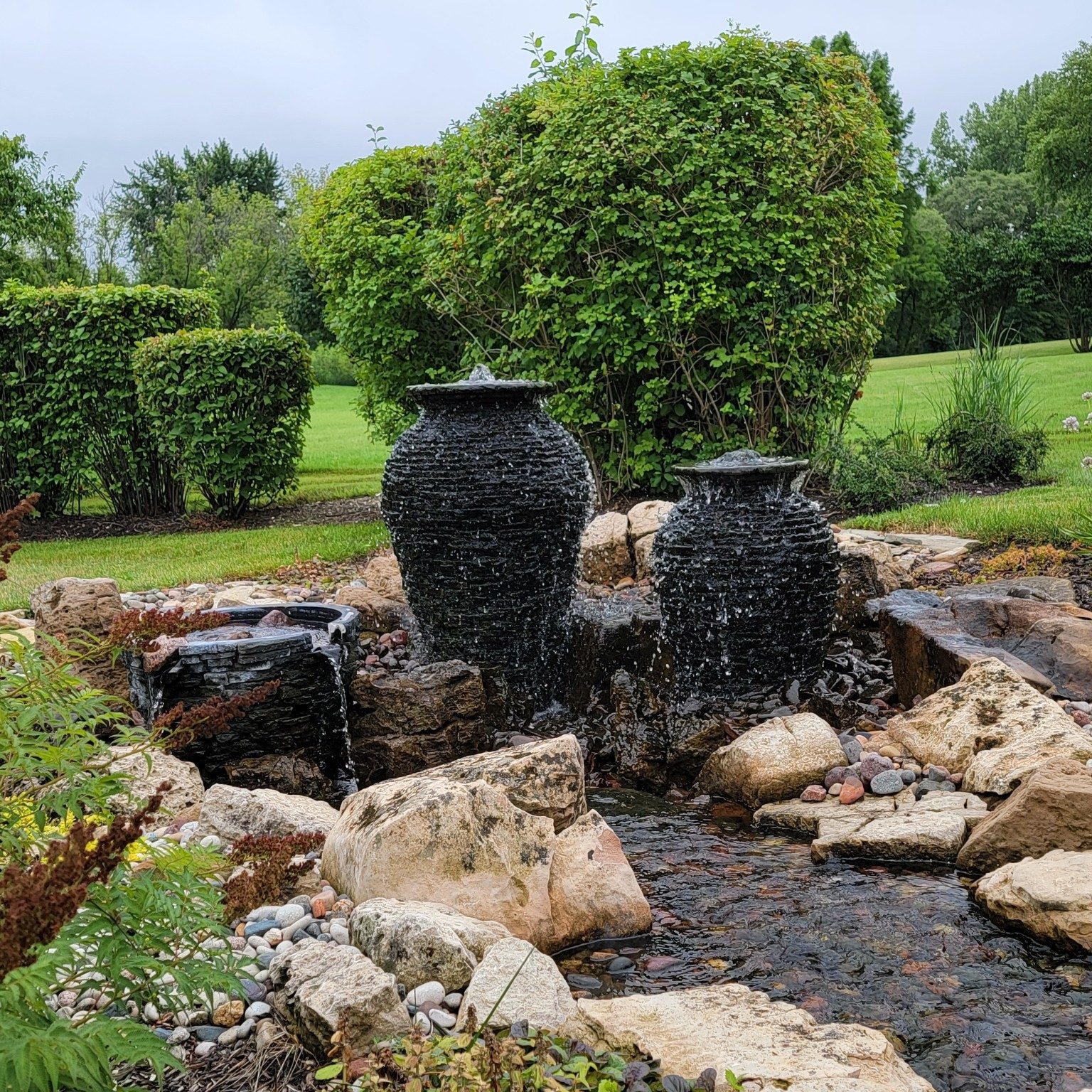 Decorative water feature with black volcanic stones in garden setting